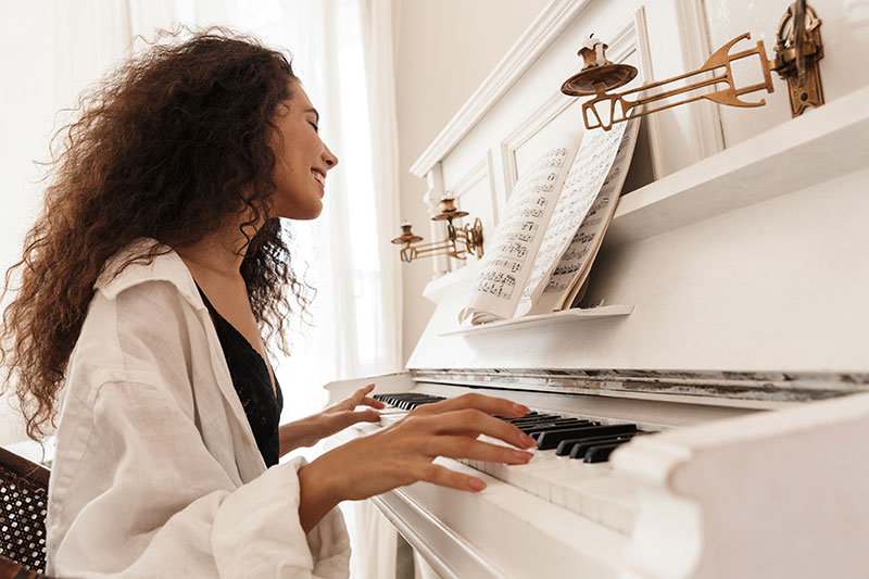 Woman enjoying playing white upright piano
