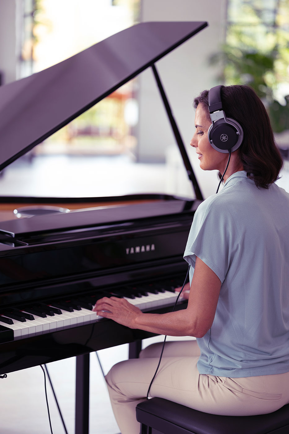 Woman playing Yamaha Clavinova piano with headphones on